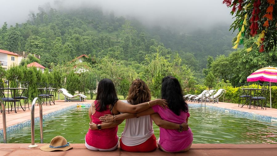 three women holding each other and looking at the fog on the mountain - neer ganga resorts