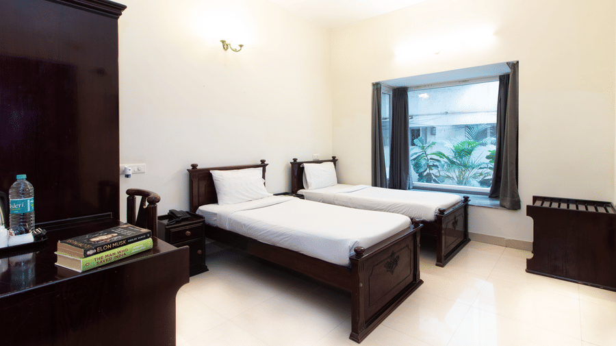 Hotel room with a double bed, an in-room amenity tray, and a window overlooking greenery at Sanctum Suites Indiranagar, Bangalore.
