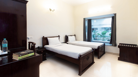 Hotel room with a double bed, an in-room amenity tray, and a window overlooking greenery at Sanctum Suites Indiranagar, Bangalore.