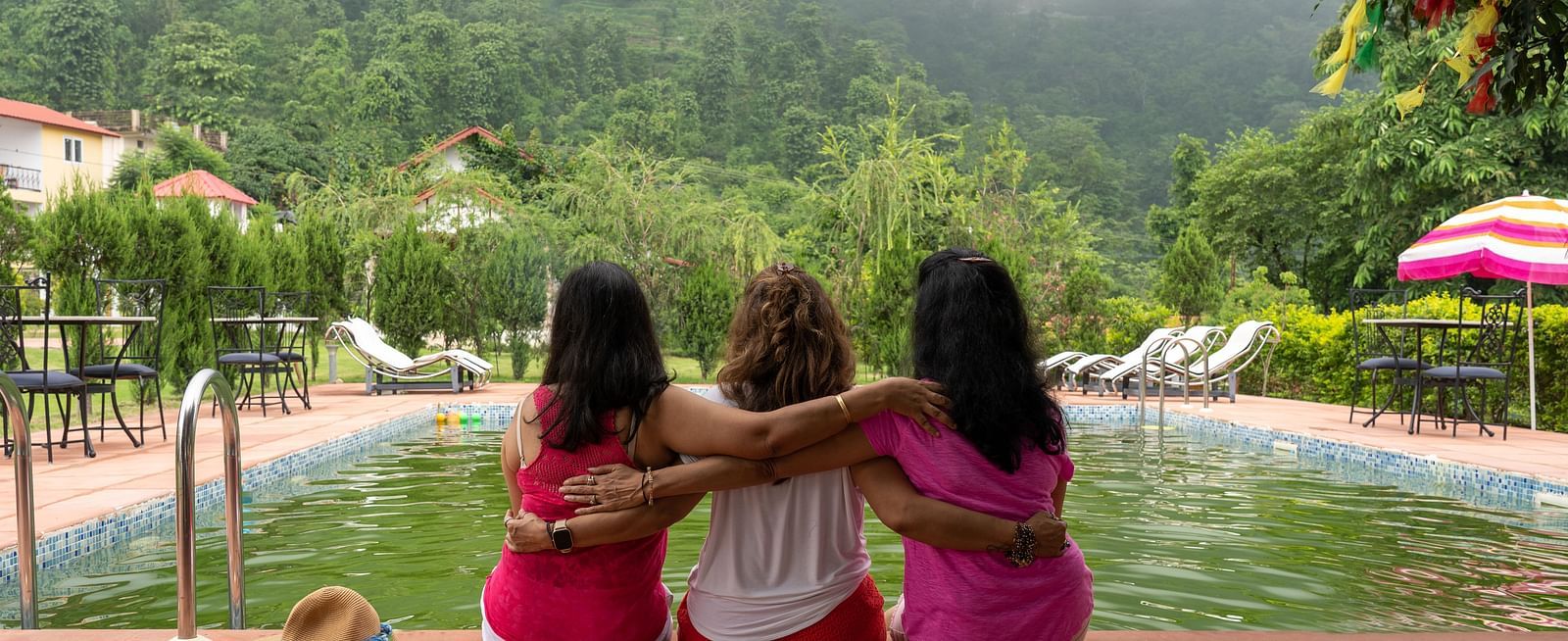 three women holding each other and looking at the fog on the mountain - neer ganga resorts