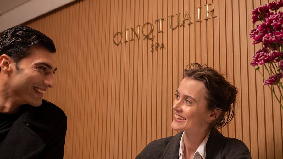 Two people smiling at each other with Cinqtuair Spa sign board in the background - The Claridges New Delhi