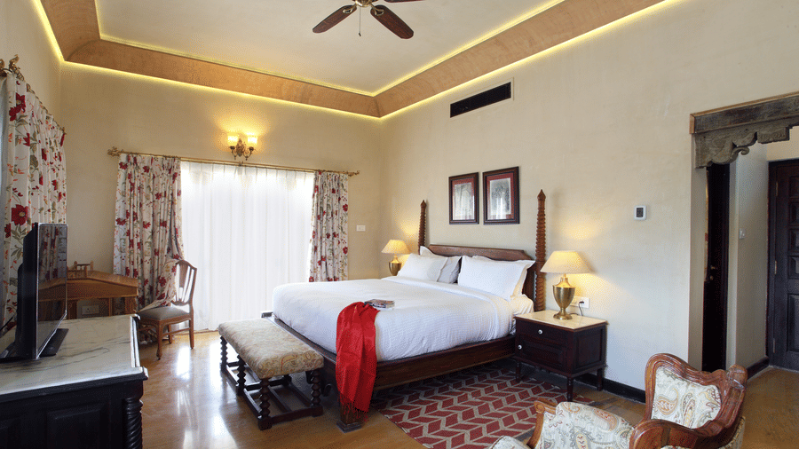 Elegant deluxe room at Juna Mahal with plush bedding, ambient lighting and spacious layout reflecting a blend of comfort and heritage charm