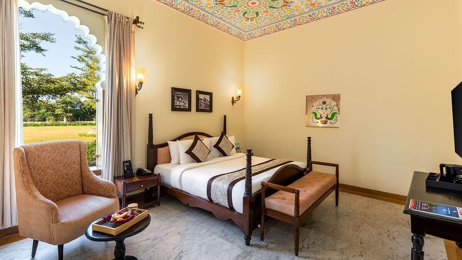 Spacious room with vintage furniture and painted ceiling at Kesar Bagh Palace.