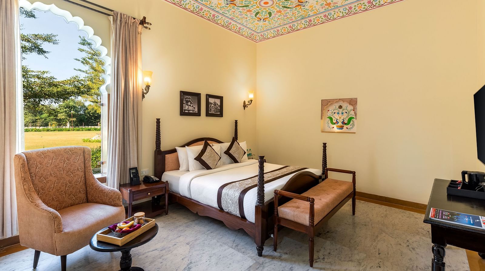 Spacious room with vintage furniture and painted ceiling at Kesar Bagh Palace.