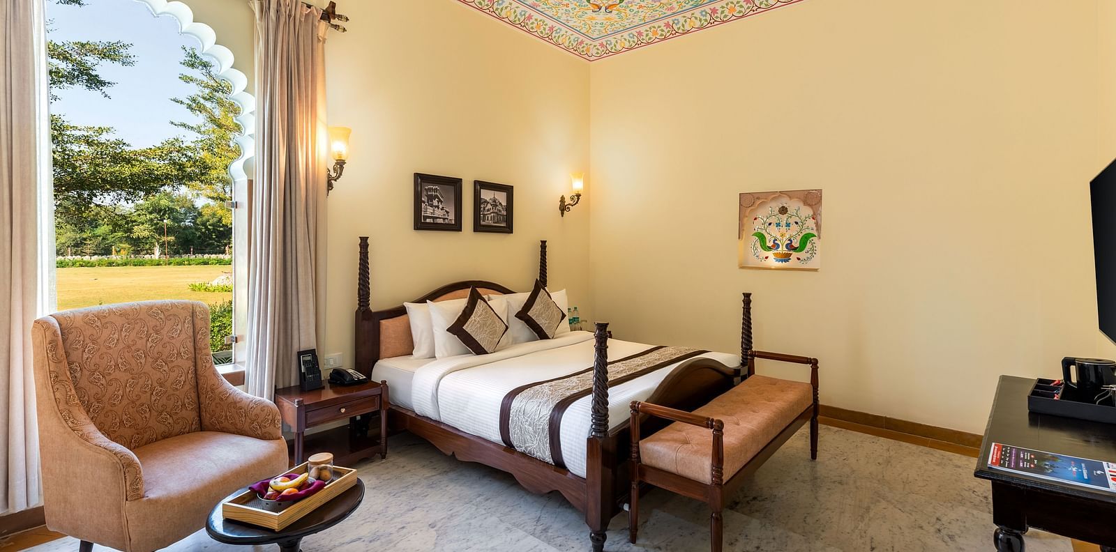Spacious room with vintage furniture and painted ceiling at Kesar Bagh Palace.