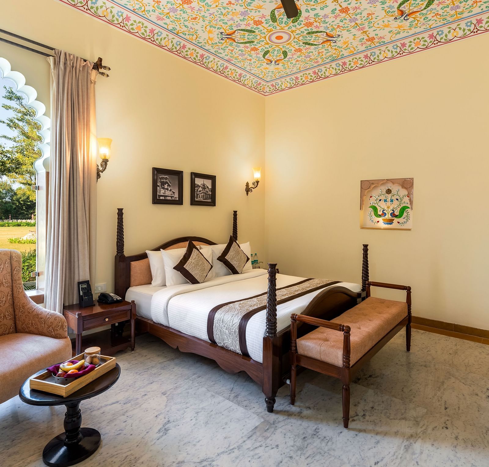 Spacious room with vintage furniture and painted ceiling at Kesar Bagh Palace.