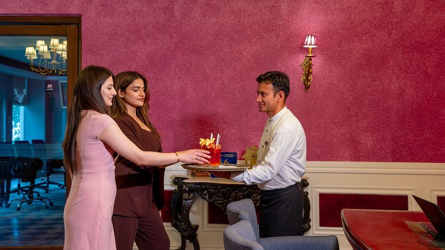 An image of two women standing at the counter before the receptionist - The Manor Luxury Hotel, Shimla