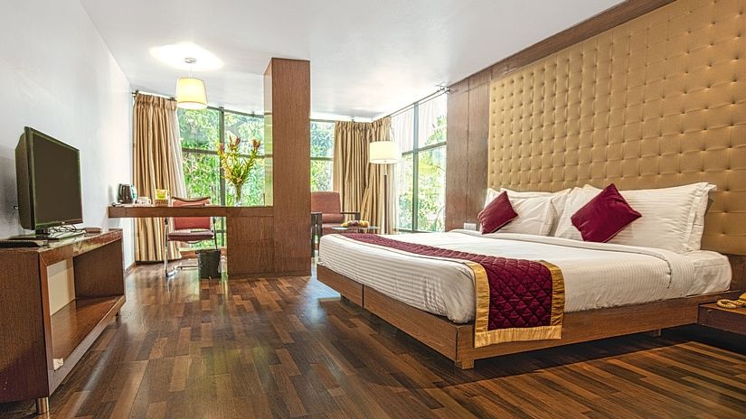 A photo of a hotel room with a king size bed, a TV, a desk, and a large window.