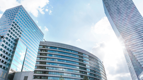 view of three office buildings with the sun shining behind them