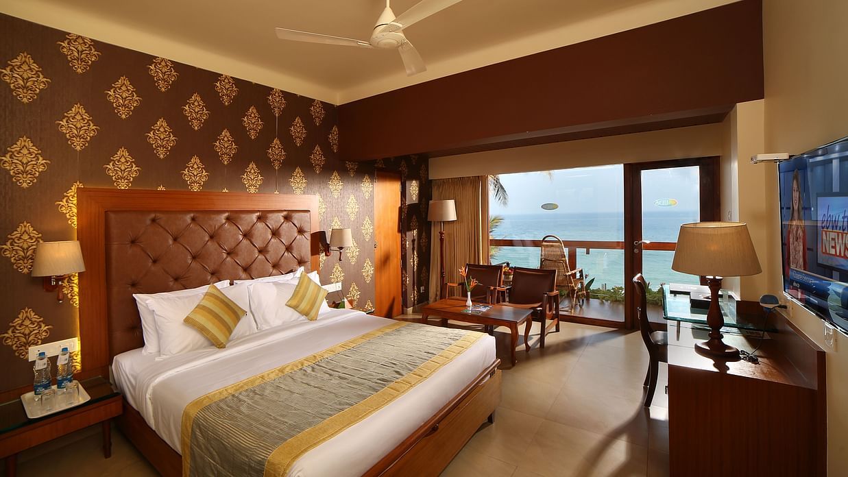 Coastal View Rooms at Uday Samudra Leisure Beach Hotel, Kovalam, features a king-size bed, seating area, television, and a balcony with an ocean view.
