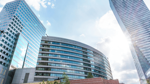 view of three office buildings with the sun shining behind them