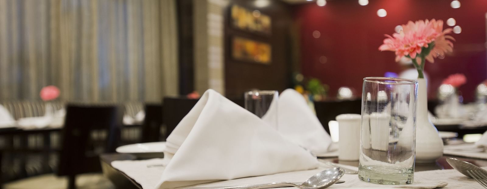 Close-up shot of cutlery neatly arranged on a dining table in a enclosed dining space at The Manor, Bareilly