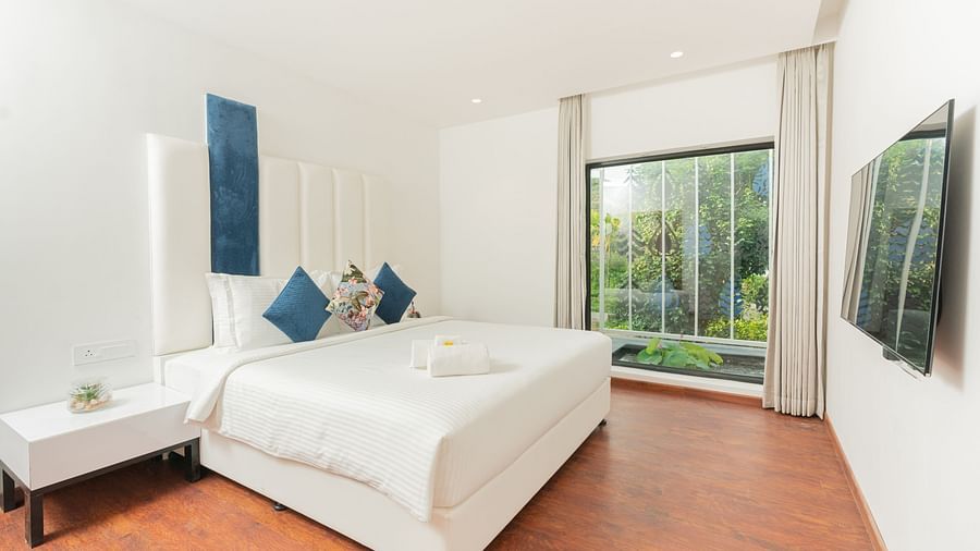 image of a bedroom of the family villa two bedroom with a huge window in the corner with lush green views - Darza Resorts