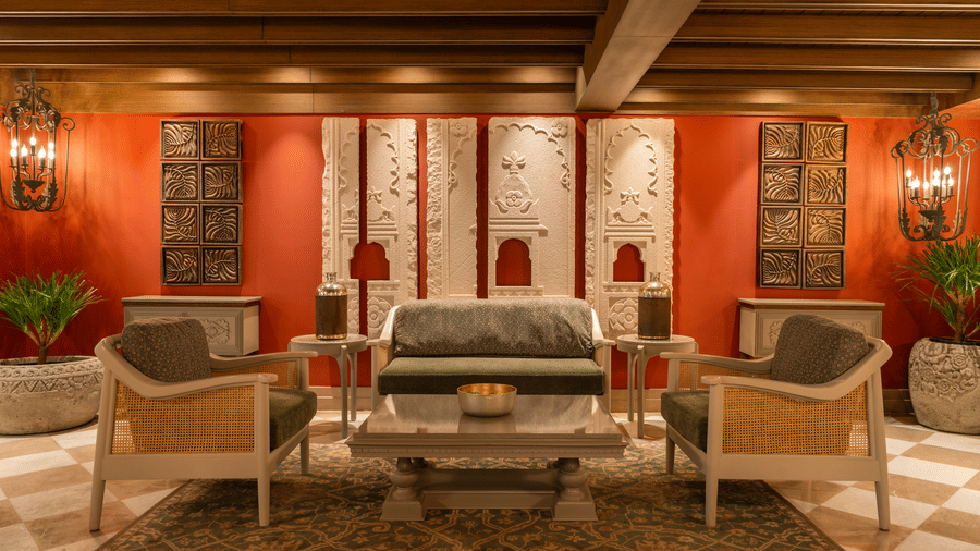 The lobby seating area of The Evren with armchairs, side tables, wall panels, and indoor plants.