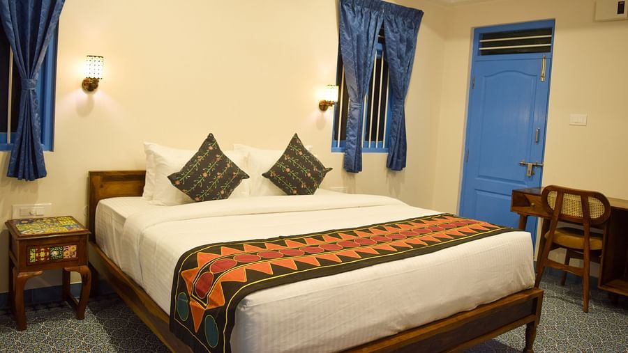 A hotel room with a double bed, blue accents, and traditional Indian textile patterns - Ibex Resorts, Coimbatore (Kakarla)