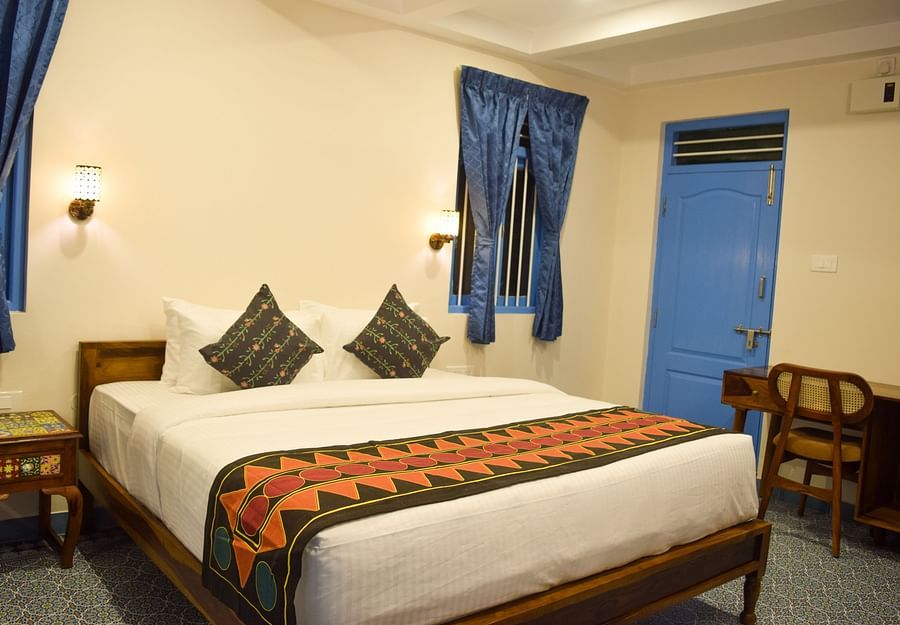 A hotel room with a double bed, blue accents, and traditional Indian textile patterns - Ibex Resorts, Coimbatore (Kakarla)