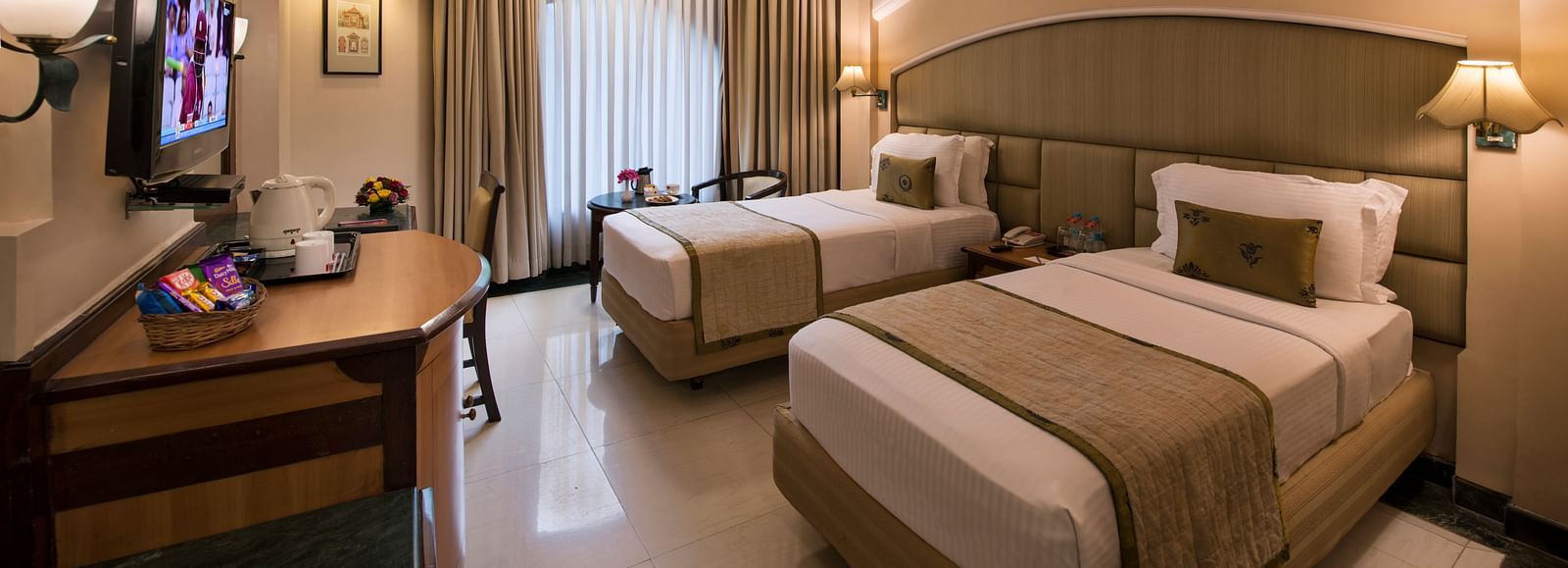 Hotel room with a seating area, a plush armchair, a lamp, and a decorative mirror - Lords Inn Vadodara