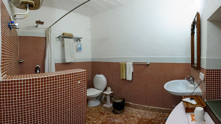 Hill Fort Kesroli 14th Century Alwar - interior view of the Pitambar Bathroom with brown coloured tiles featuring a commode, wash basin, water heater and a shower area