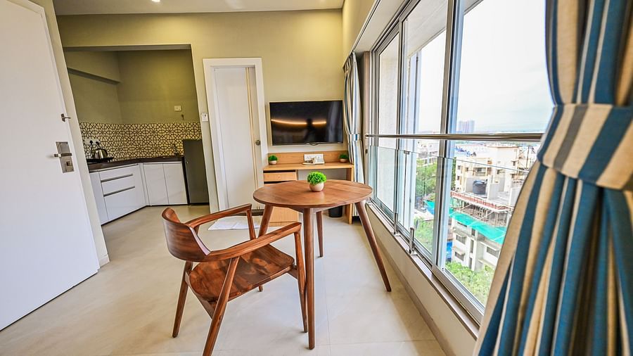 An image of a Studio Room featuring a kitchen, a seating area with tables and chairs, and a large window in front of it - Indie Stays Studio, Chembur