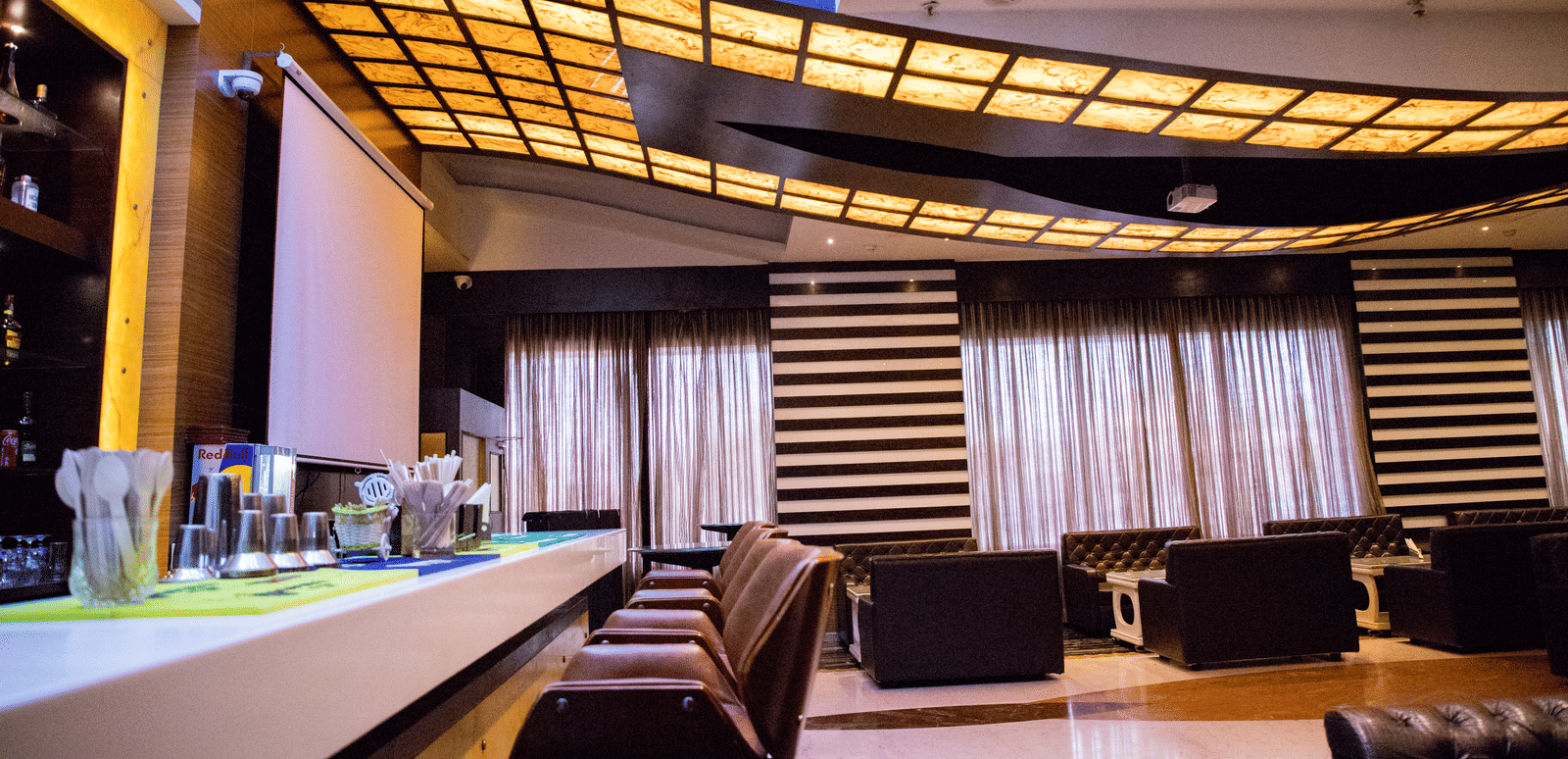 Side view shot of a bar counter with several elevated chairs lined on the bar counter at the Benzz Park, Vellore.