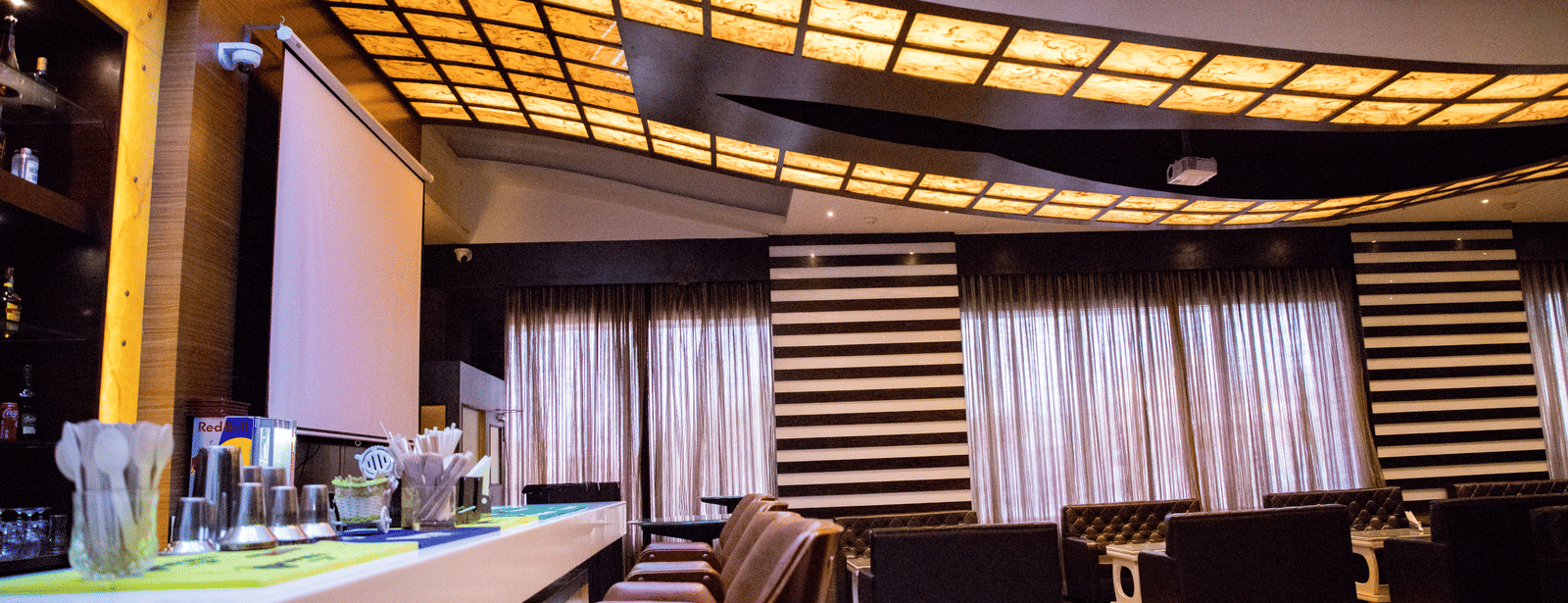 Side view shot of a bar counter with several elevated chairs lined on the bar counter at the Benzz Park, Vellore.