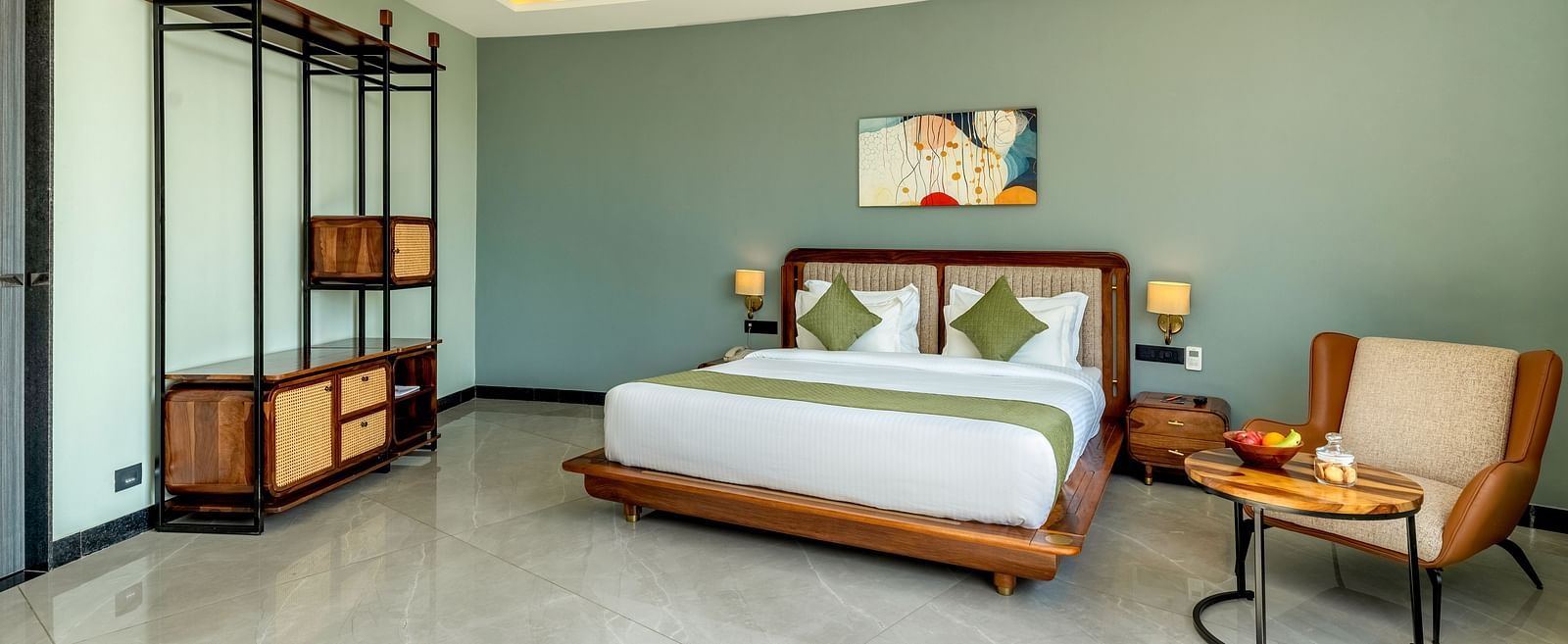 Pool View Room featuring a king size bed with a green and white patterned bedspread, wooden furniture, and a large window with sheer curtains at The Qualia Resort Club & Brewery, Udaipur.