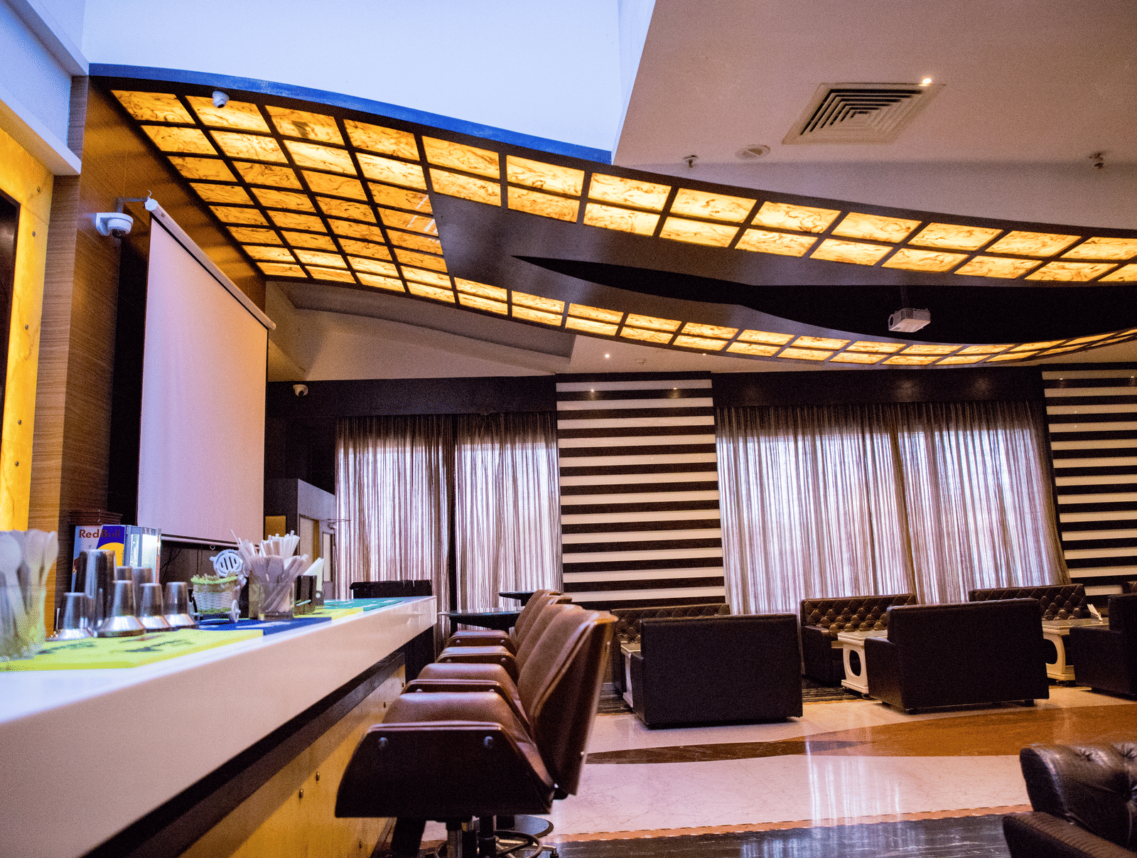 Side view shot of a bar counter with several elevated chairs lined on the bar counter at the Benzz Park, Vellore.