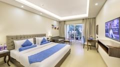a double bedroom featuring a king size bed, a flat screen television, a balcony and ambient lighting - Golden Tulip, Candolim, Goa