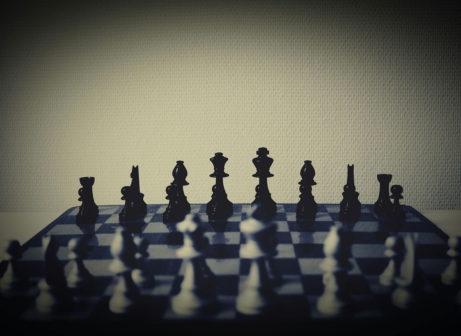 A dimly lit photograph captures a chess set with pieces.