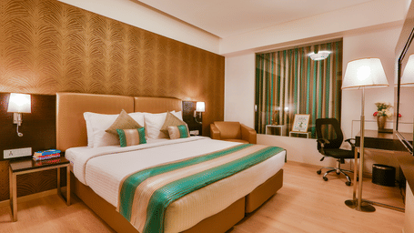 A room with a neatly-made bed and a work desk and chair at T24 Residency, Andheri East (Terminal 2), in Mumbai.