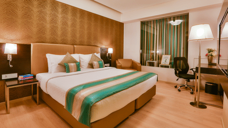 A room with a neatly-made bed and a work desk and chair at T24 Residency, Andheri East (Terminal 2), in Mumbai.