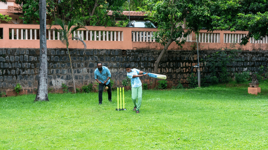 A boy playing  cricket on the grass field.