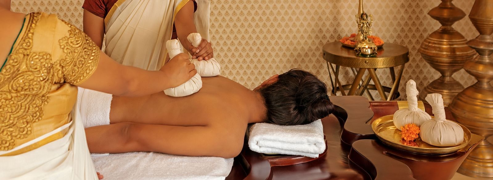 A person receiving a massage with another person standing nearby, indoor setting with decorative items - Shreyas Retreat