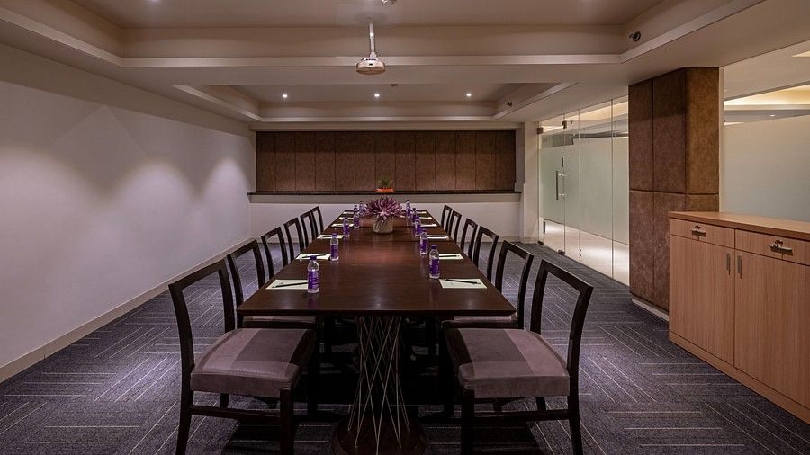 The meeting space is equipped with dark mahogany chairs and a matching table, with cabinets lining one side of the wall.