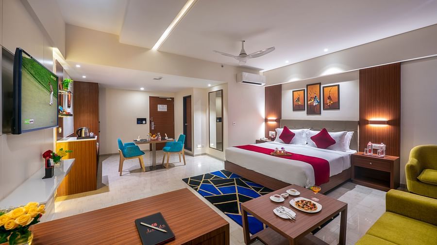 Spacious room with a huge bed, seating area, and entertainment unit - Lords Eco Inn Shapar Rajkot