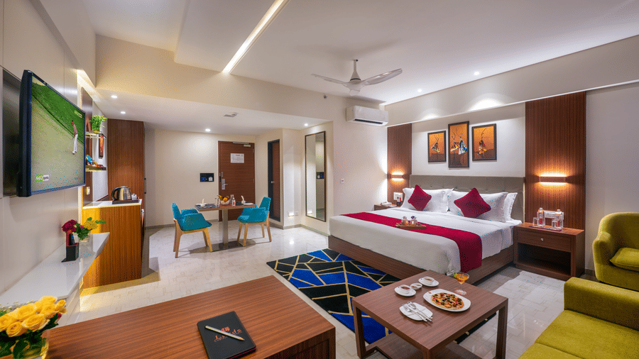 A hotel room in Lords Eco Inn Shapar Rajkot with a double bed, mini bar, TV, and a lounge chair