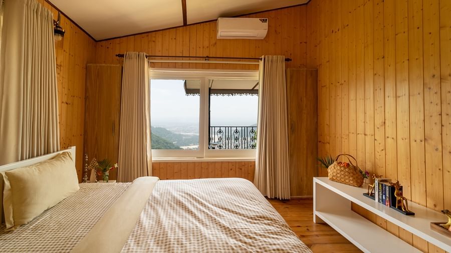 a double bed with pillows on it and an ac wall mounted inside one of the rooms - neer ganga Resorts