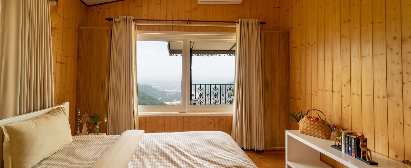 a double bed with pillows on it and an ac wall mounted inside one of the rooms - neer ganga Resorts