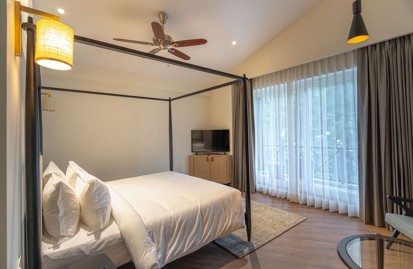 Bright bedroom with a four-poster bed and balcony access at Nivasana Manali.