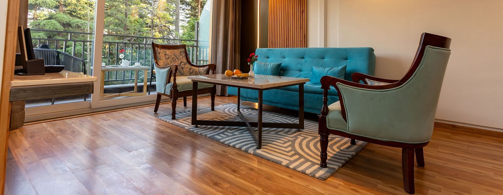 An image of a Suite with sofa set, centre table, subtle decoration using lights and an expansive glass door leading to the balcony - The Belvedere Himalayan Retreat, McLeodganj