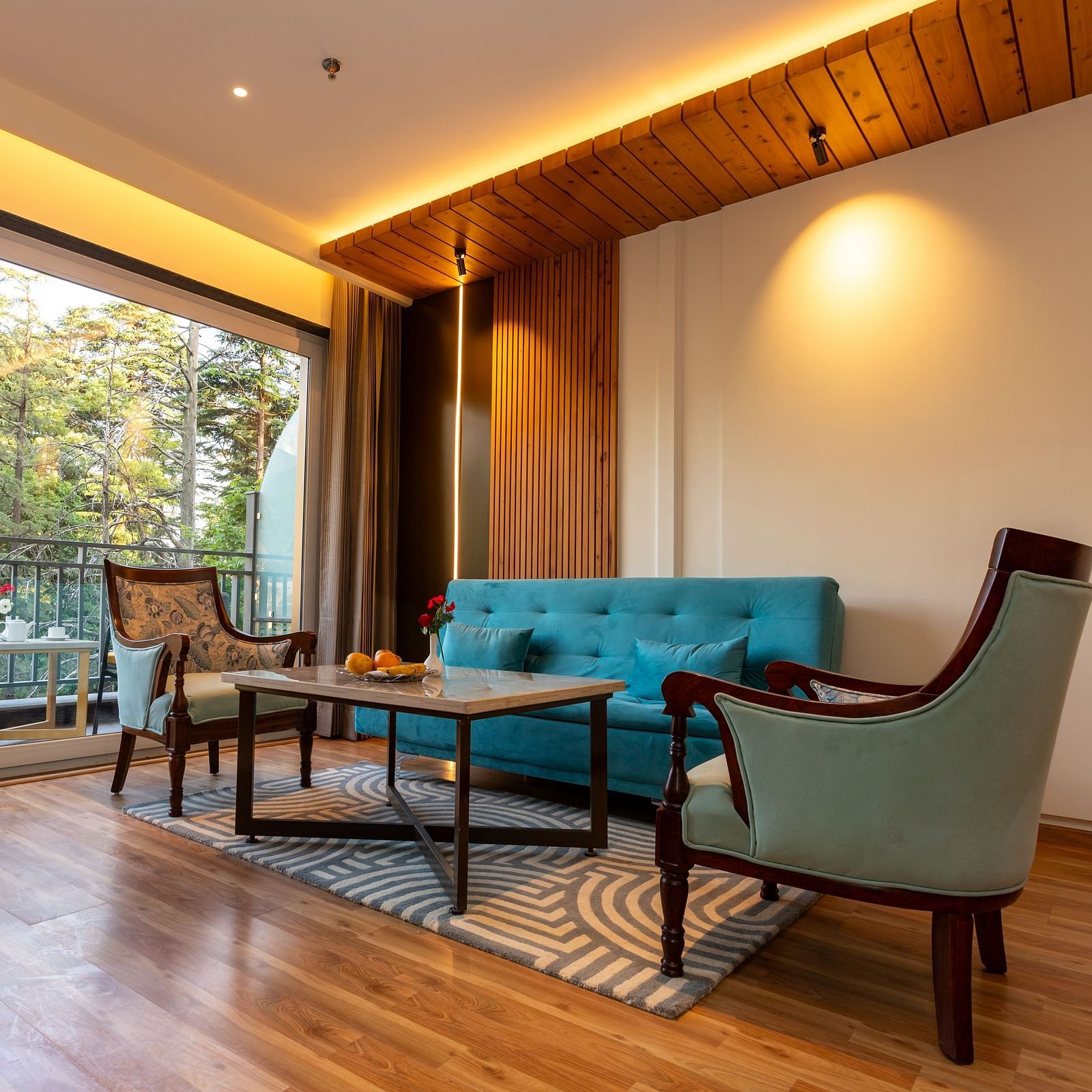 An image of a Suite with sofa set, centre table, subtle decoration using lights and an expansive glass door leading to the balcony - The Belvedere Himalayan Retreat, McLeodganj