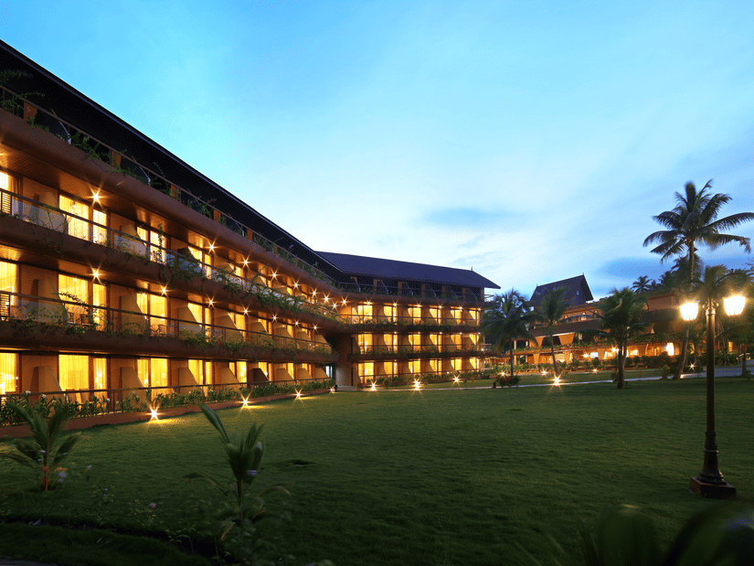 The building of Uday Backwater Resort lit up in warm lights during late evening