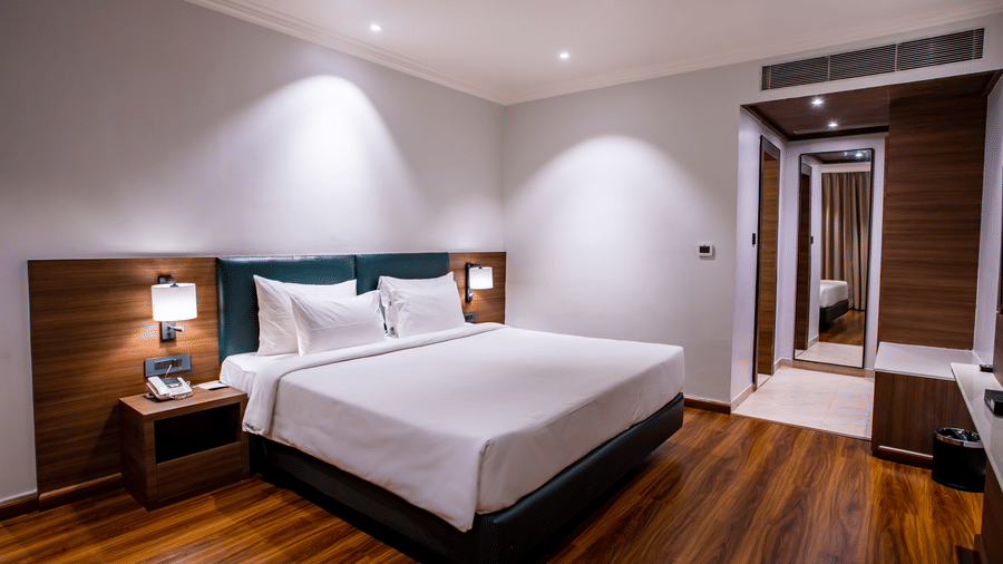 A double bed with side tables and lamps inside one of the rooms - Wedlock Greens Hotel Resorts Dhanbad