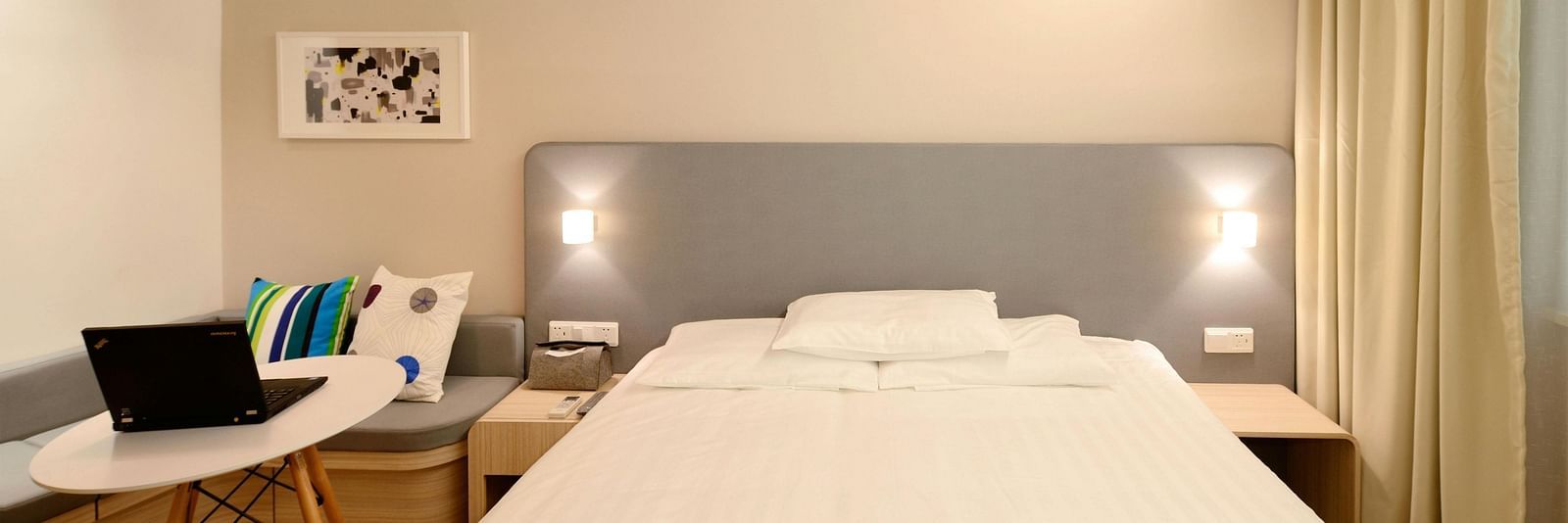 A close up shot of a large bed in a hotel room with a sofa and coffee table beside it