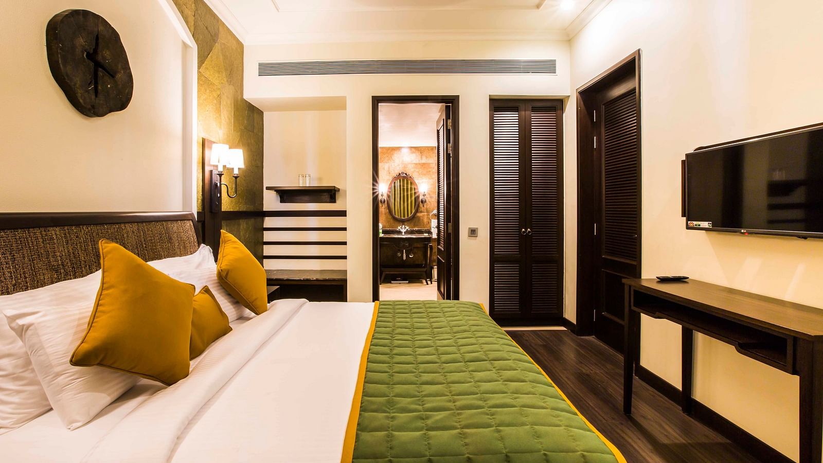 Bed with white sheets and green comforter inside one of our rooms - Rhythm Lonavala