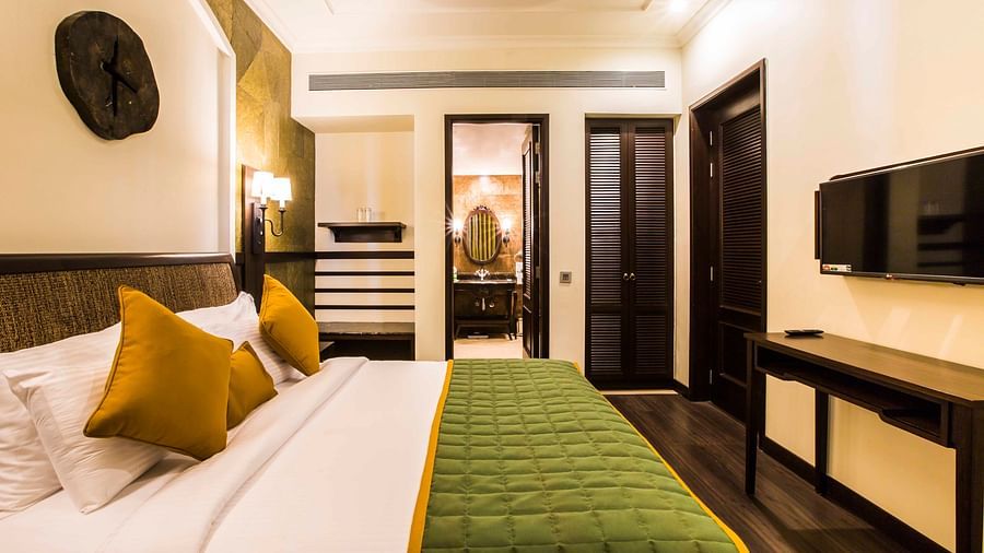 Bed with white sheets and green comforter inside one of our rooms - Rhythm Lonavala