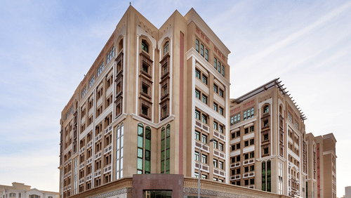 Facade view of La Maison Hotel, Doha, featuring a blue sky in the background, a hotel near Doha Corniche.