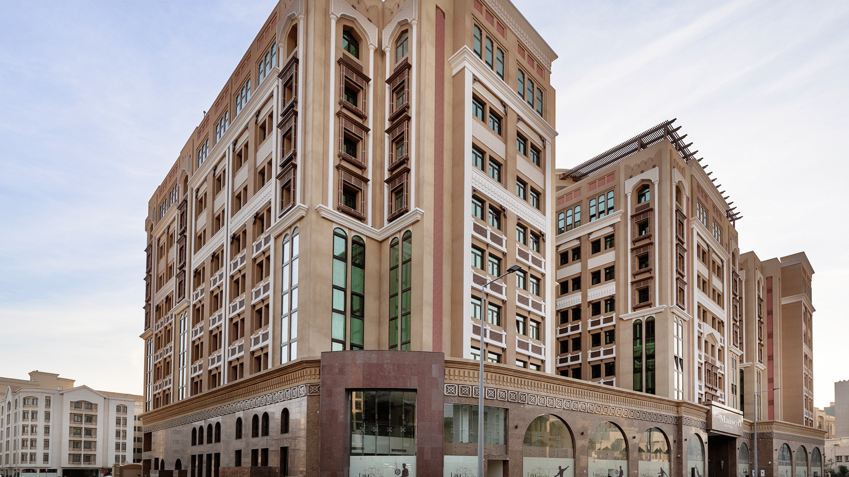 Facade view of La Maison Hotel, Doha, featuring a blue sky in the background, a hotel near Doha Corniche.