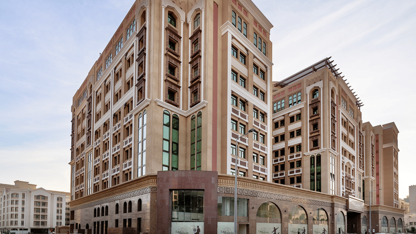 Facade view of La Maison Hotel, Doha, featuring a blue sky in the background, a hotel near Doha Corniche.