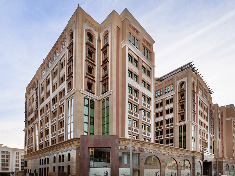 Facade view of hotel near Doha Airport set against a clear blue sky, showcasing a welcoming surrounding | La Maison Hotel, Doha